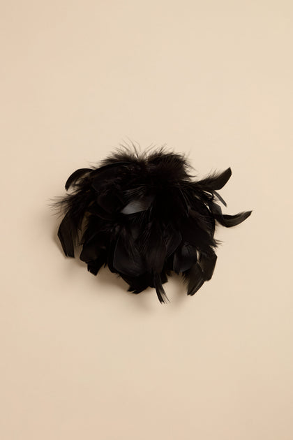 A Feather Corsage made of a cluster of black feathers styled as a statement accessory.
