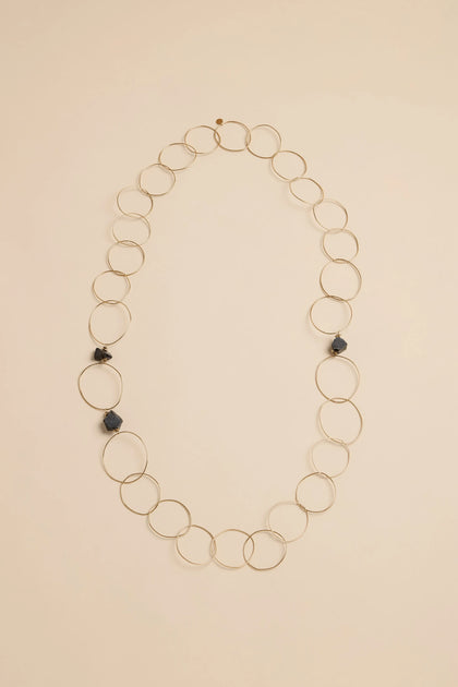 Midnight Stone Link Necklace featuring large, gold-tone interlocking circular links accented with three dark, rough-cut stones.