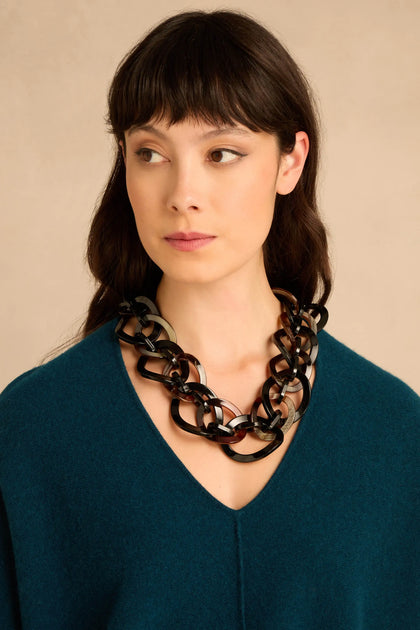 A woman wearing a Short Resin Link Necklace featuring large, translucent brown and black resin links.