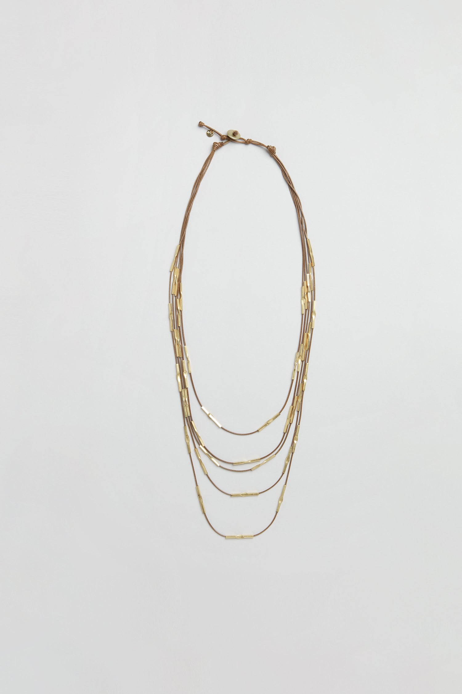 Leather and Bead Cascade Necklace featuring thin multi-strand chains adorned with small rectangular hammered gold beads, displayed flat on a plain white background.