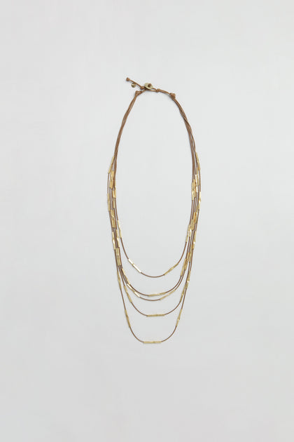 Leather and Bead Cascade Necklace featuring thin multi-strand chains adorned with small rectangular hammered gold beads, displayed flat on a plain white background.