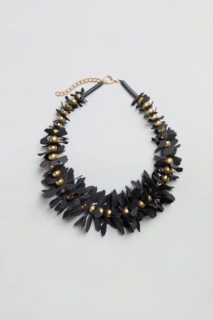 Flower Bead Necklace showcasing black floral elements with gold accent beads and an adjustable gold chain clasp, designed in a collar-length style and presented on a plain light gray background.