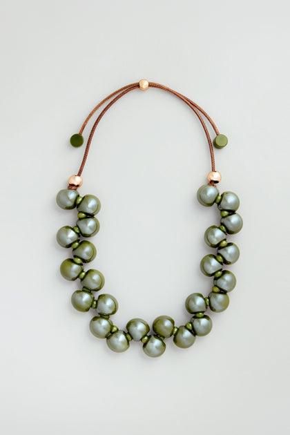 The Macrame Resin Bead Necklace features large, round olive-green resin beads on a brown cord with gold accents and an adjustable closure for a perfect fit.