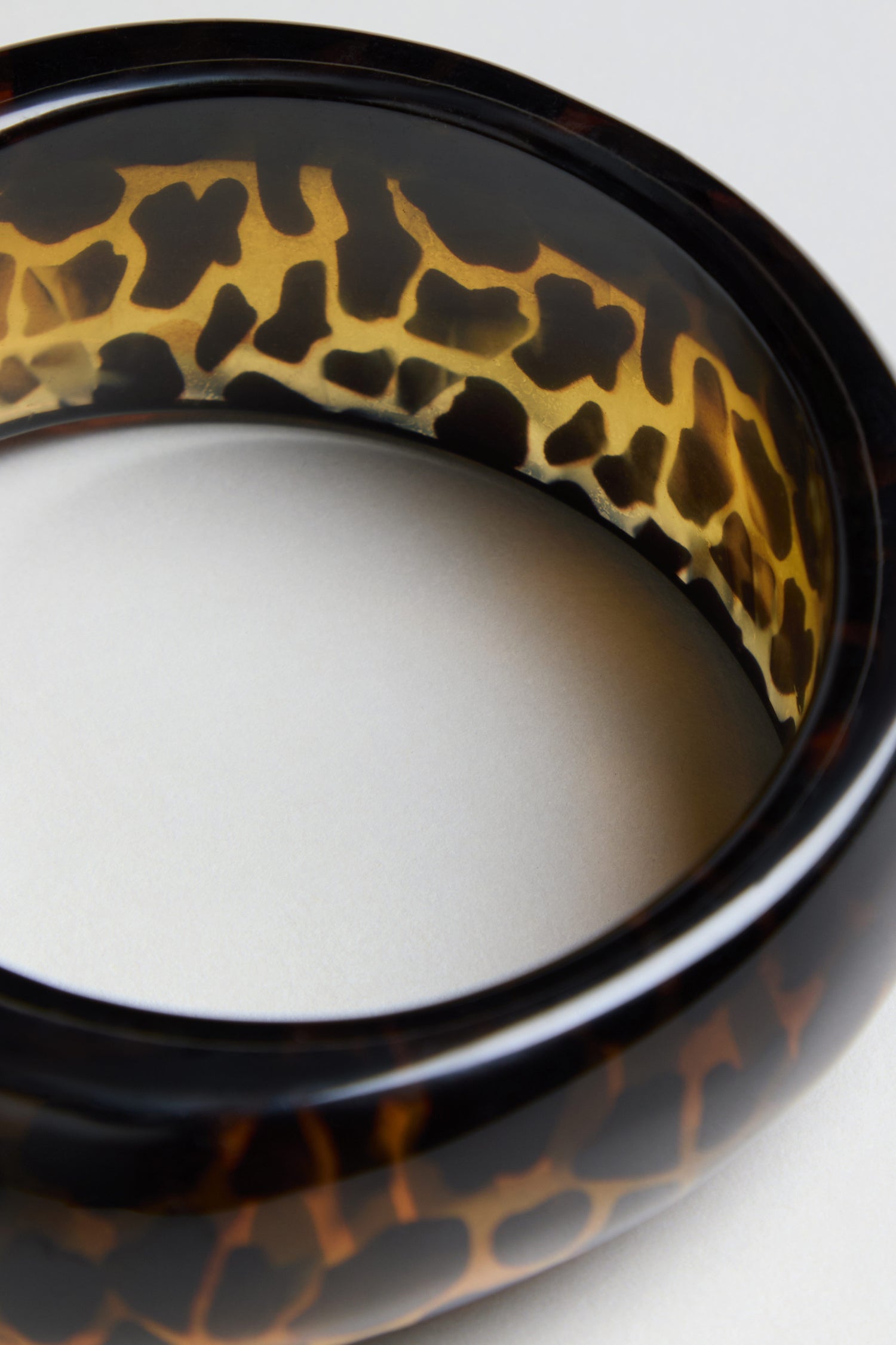 Close-up of the Leopard Bangle, featuring a round, glossy resin design with a brown and black leopard print pattern on a neutral background.