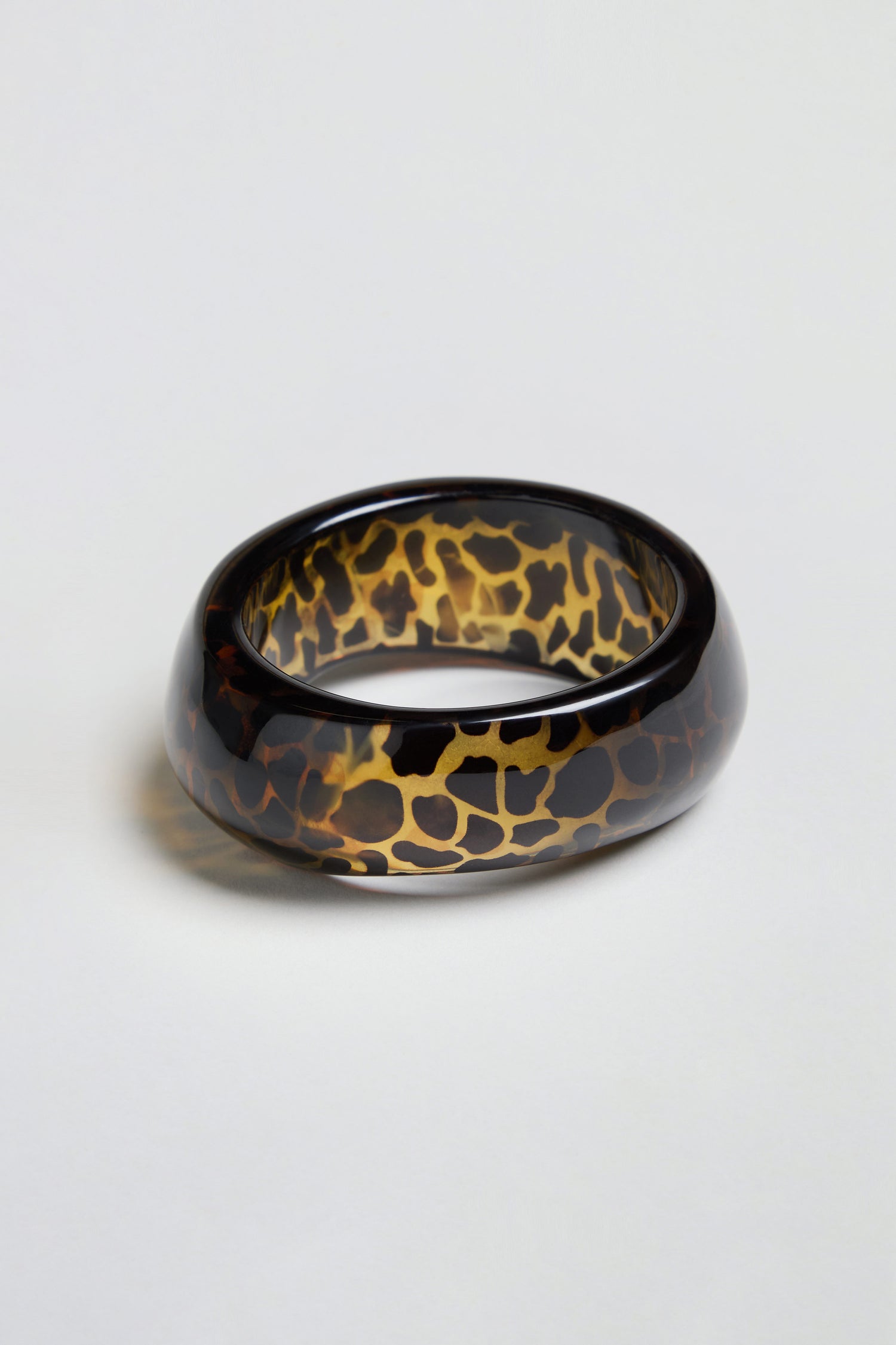Leopard Bangle – a chunky, oval-shaped resin accessory featuring a glossy finish and an eye-catching tortoiseshell pattern, showcased on a plain white background.
