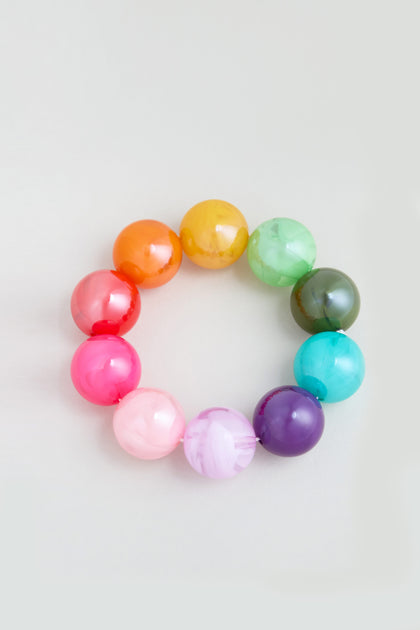The Colour Pop Resin Spheres Bracelet features ten glossy, marble-like resin beads in vibrant colors arranged in a circle, resembling a chunky bracelet, displayed against a plain light background.