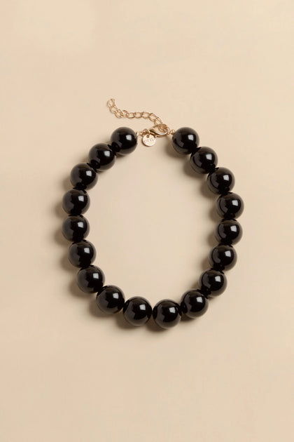 Short Spheres Necklace featuring large, smooth black beads with an adjustable gold-tone clasp and extender chain.