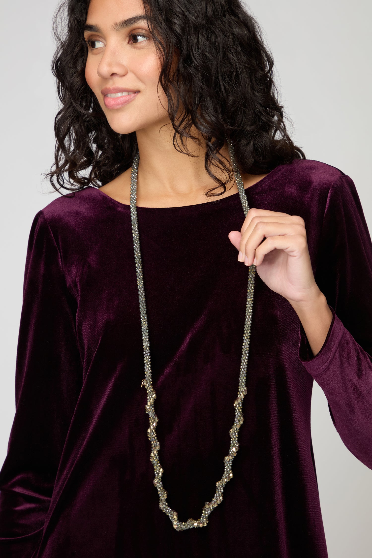 A woman wearing the Glacier Spiral Necklace and a purple velvet top looks to the side with a neutral expression.