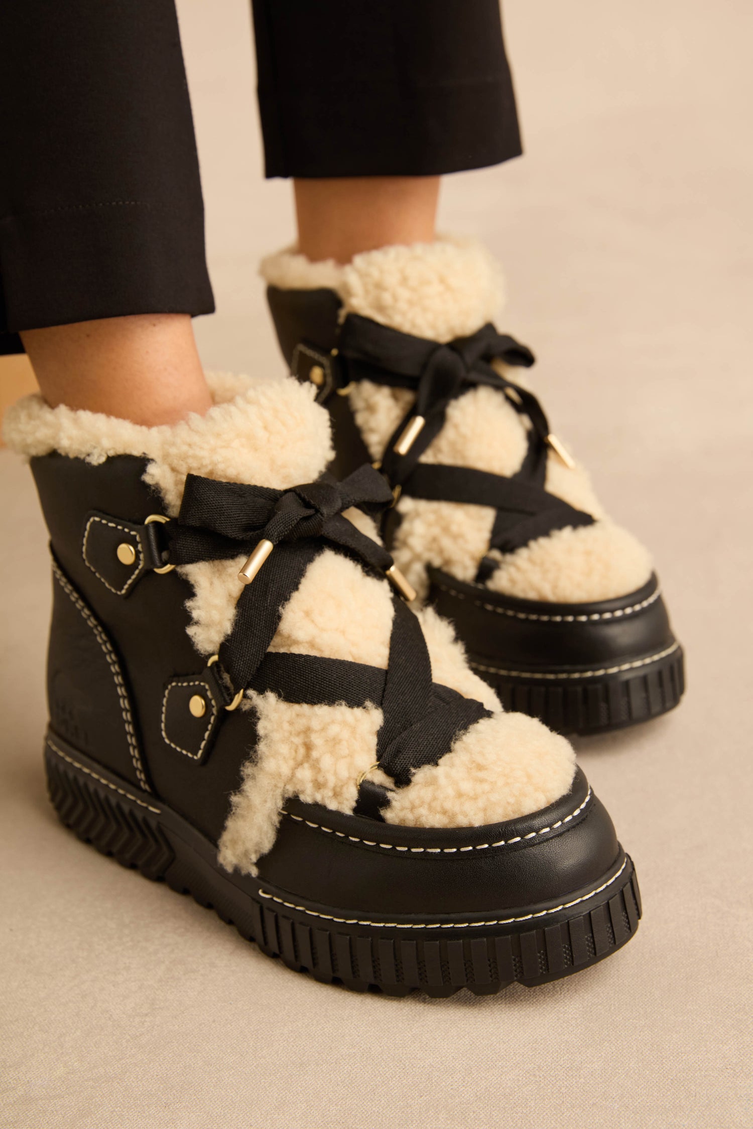 Leather Alpine Boots in black with a cream-colored faux shearling tongue, black ribbon laces, and thick rubber platform soles.