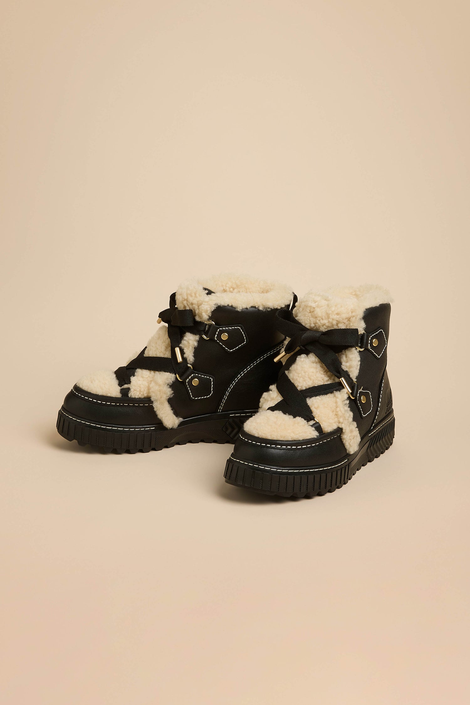 Leather Alpine Boots in black leather with a cream shearling tongue, black lace-up detailing, and a thick, lugged sole.