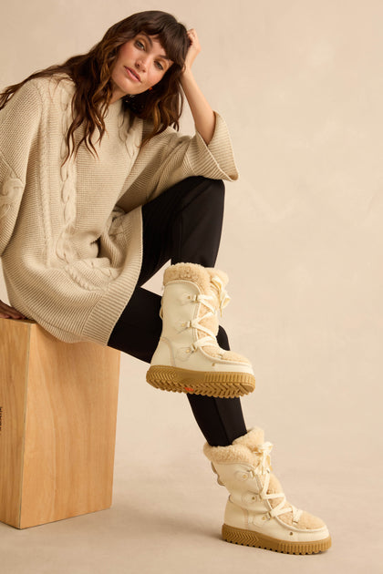 Long Leather Alpine Boots in cream-colored, waterproof leather with lace-up detailing, genuine shearling lining, and lugged rubber soles.