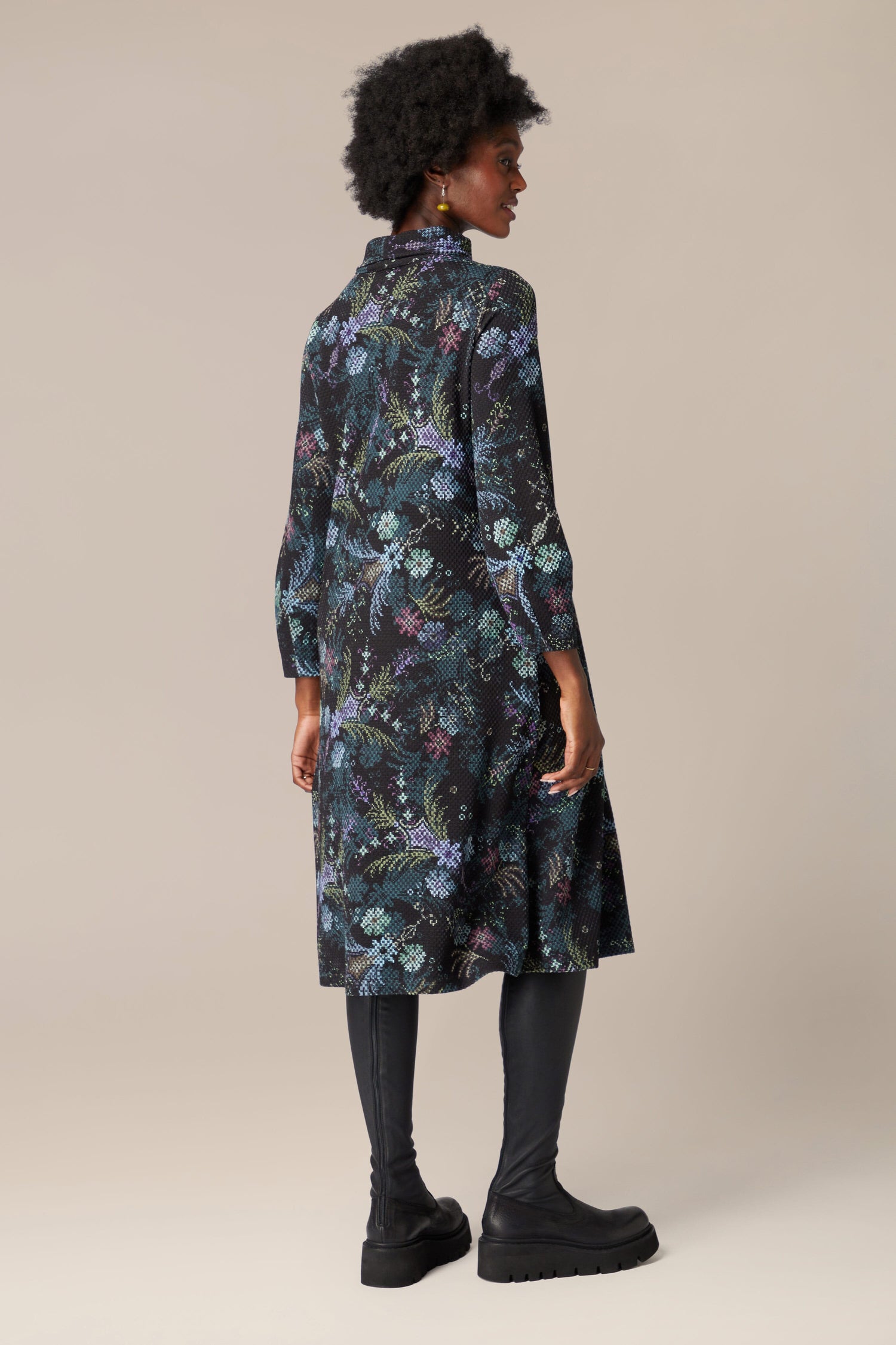 The back view of a woman wearing the Pixelated Tapestry Jersey Dress adorned with a floral print in deep hues.