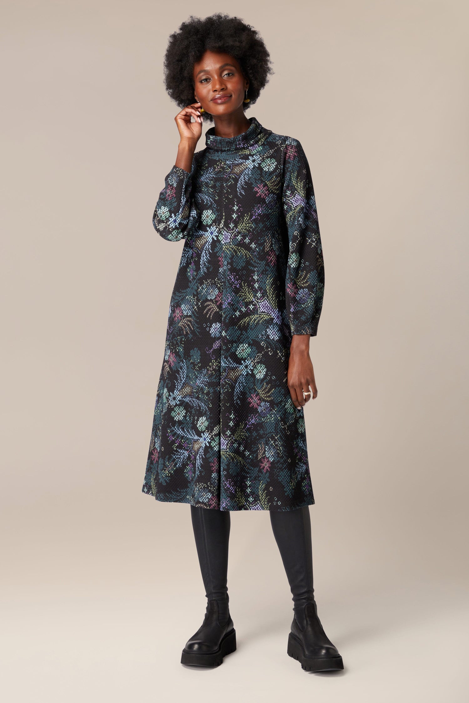 The woman is elegantly clad in a floral print shirt dress, adorned with vibrant and deep hues, resembling a Pixelated Tapestry Jersey Dress.