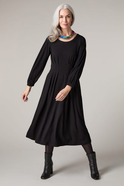 A woman wearing a Fluid Crepe Pleat Waist Dress with precise pleats.