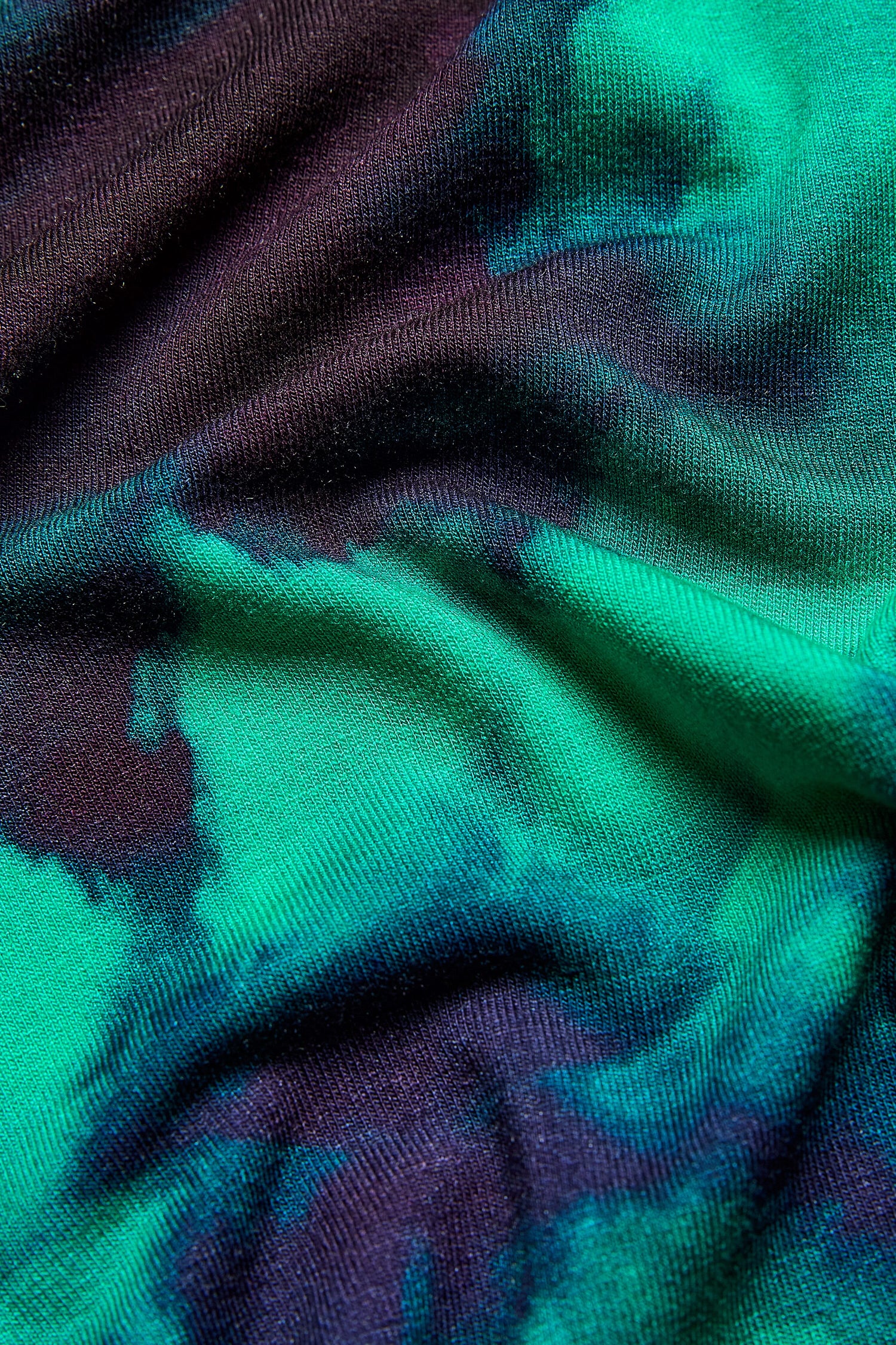 A close up of a green and blue tie dyed fabric with a Jewelled Sky Jersey Dress print.