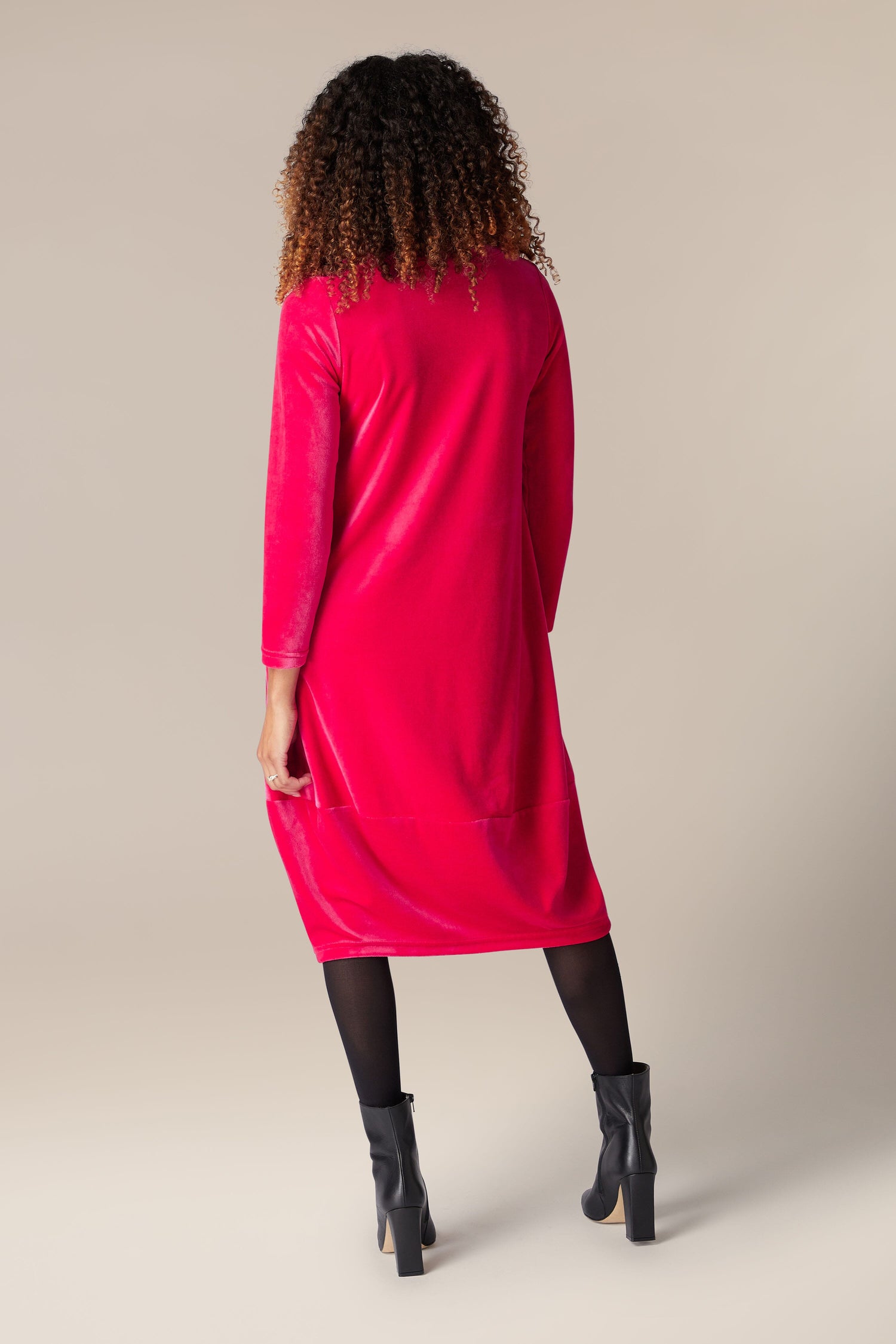 The back view of a woman wearing a luxury pink Velvet Jersey Bubble Hem Dress.