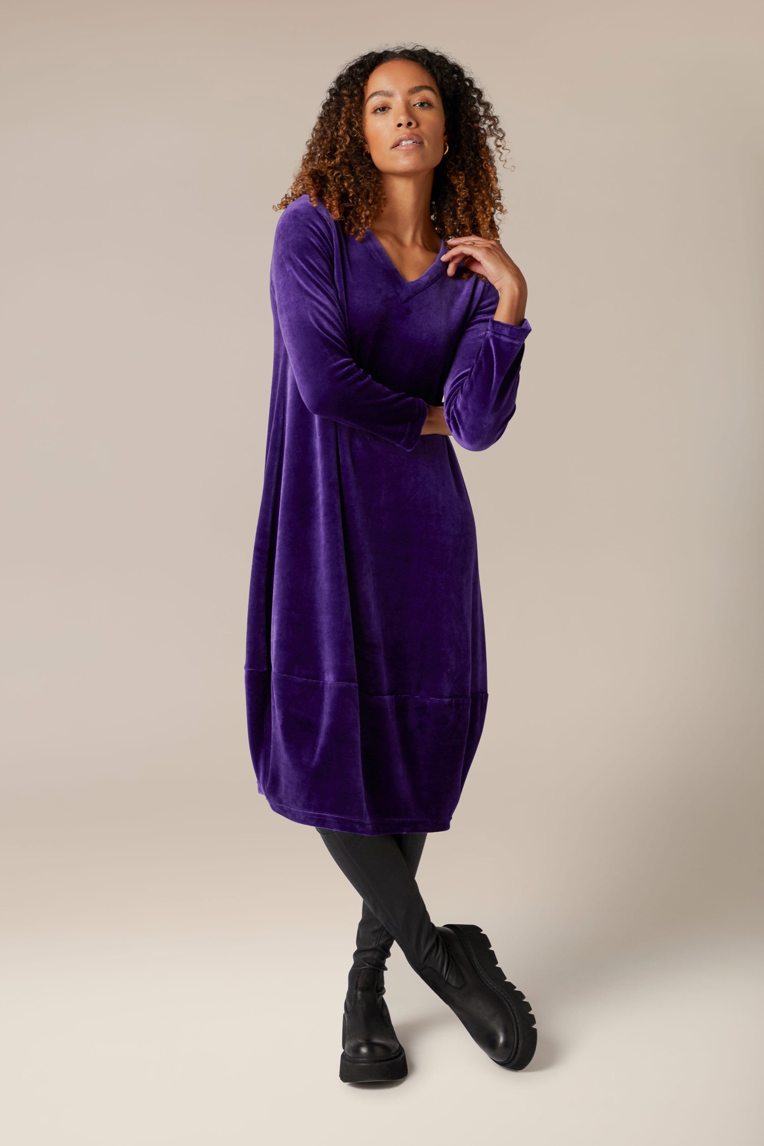 A woman in a luxurious purple Velvet Jersey Bubble Hem Dress striking a pose for a photo.