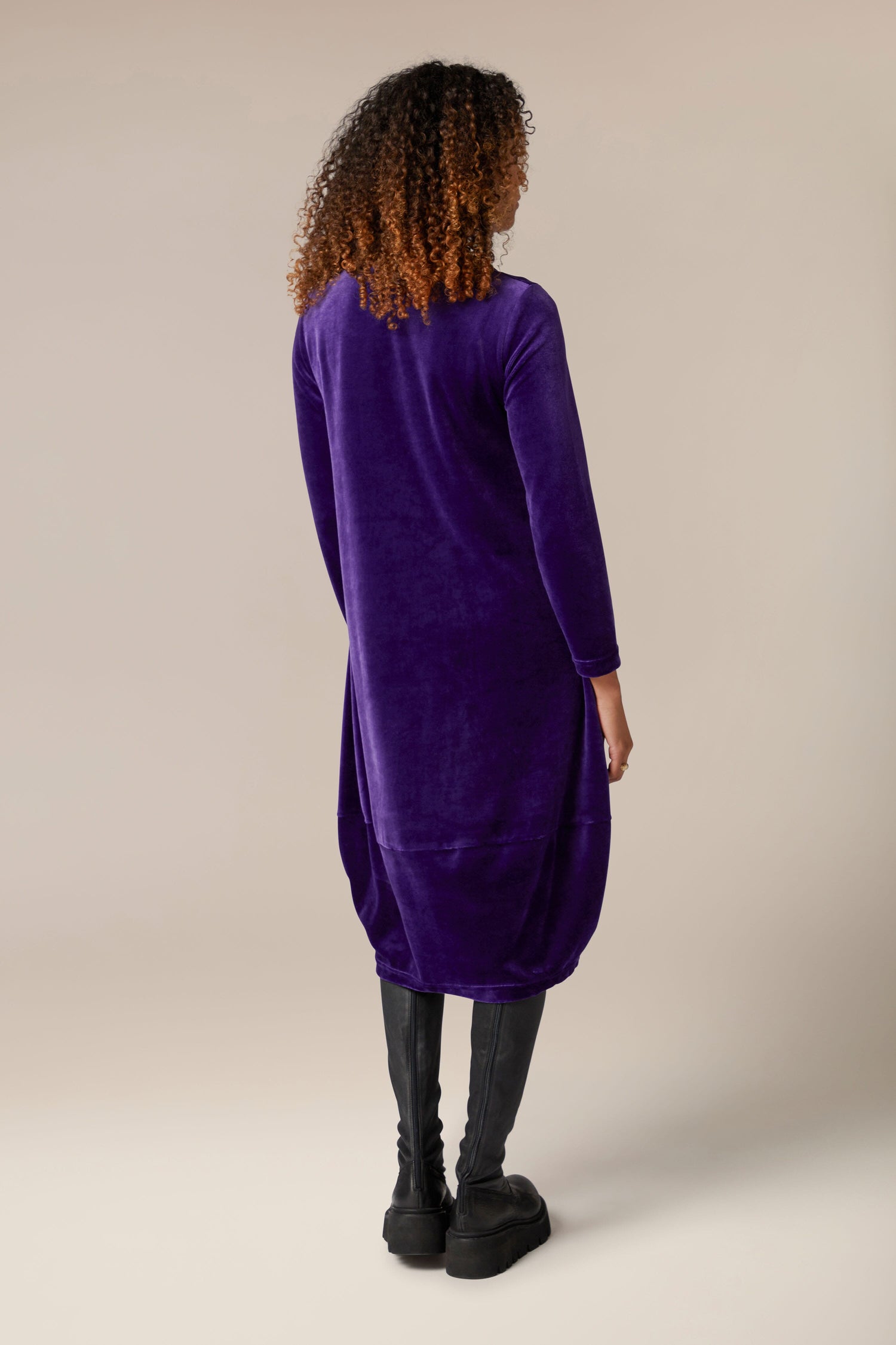 The back view of a woman wearing a luxurious Velvet Jersey Bubble Hem Dress.