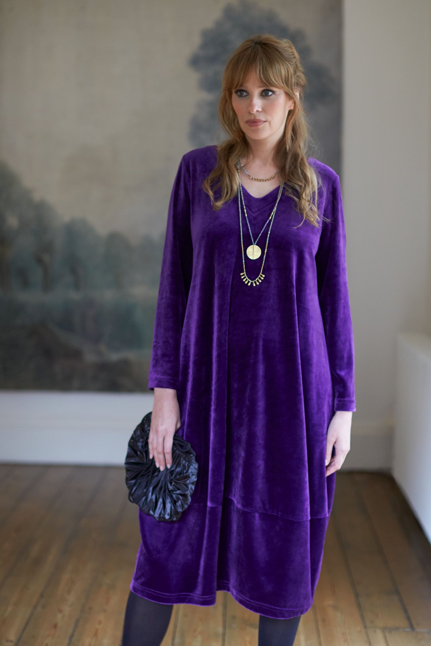 A woman in a luxurious Velvet Jersey Bubble Hem Dress standing in a room.