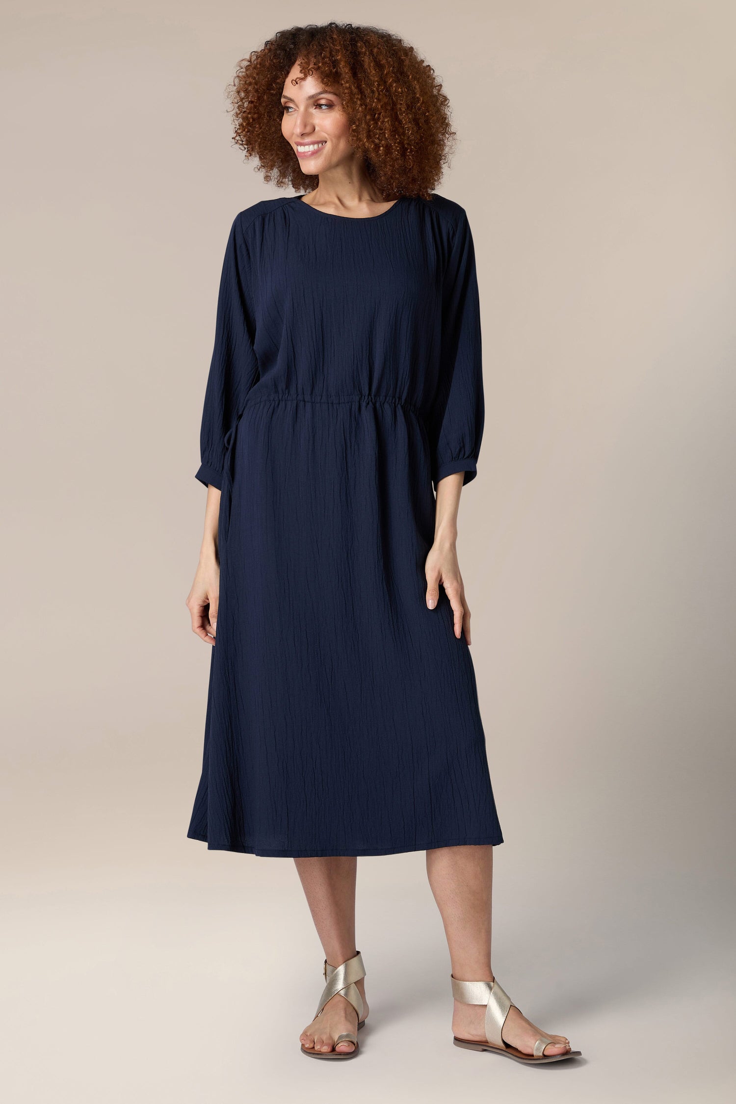 A woman wearing a navy Crinkle Soft Viscose Flared Dress and sandals.