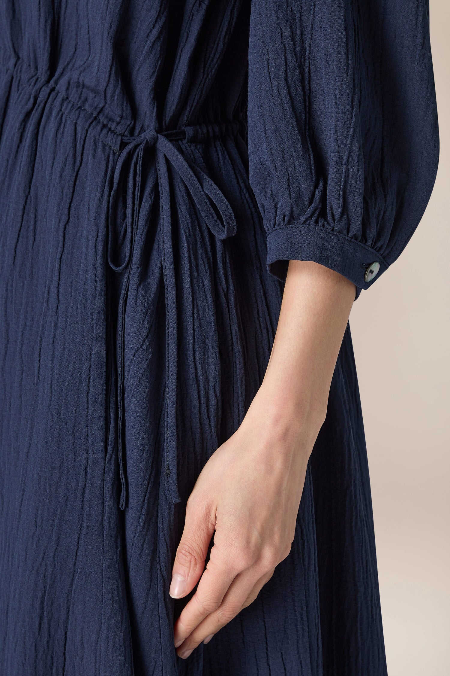 A chic woman wearing a blue Crinkle Soft Viscose Flared Dress with a sleeve.