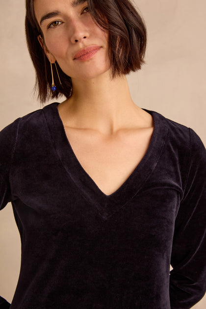 Woman with short dark hair wearing the Night Velvet Jersey Maxi Dress, crafted from cotton-rich velvet in a V-neck design, paired with a long earring and standing against a neutral background.