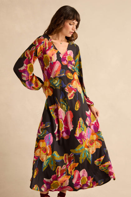 A woman wearing a black, long-sleeved, floor-length Pixelated Floral Flared Dress.
