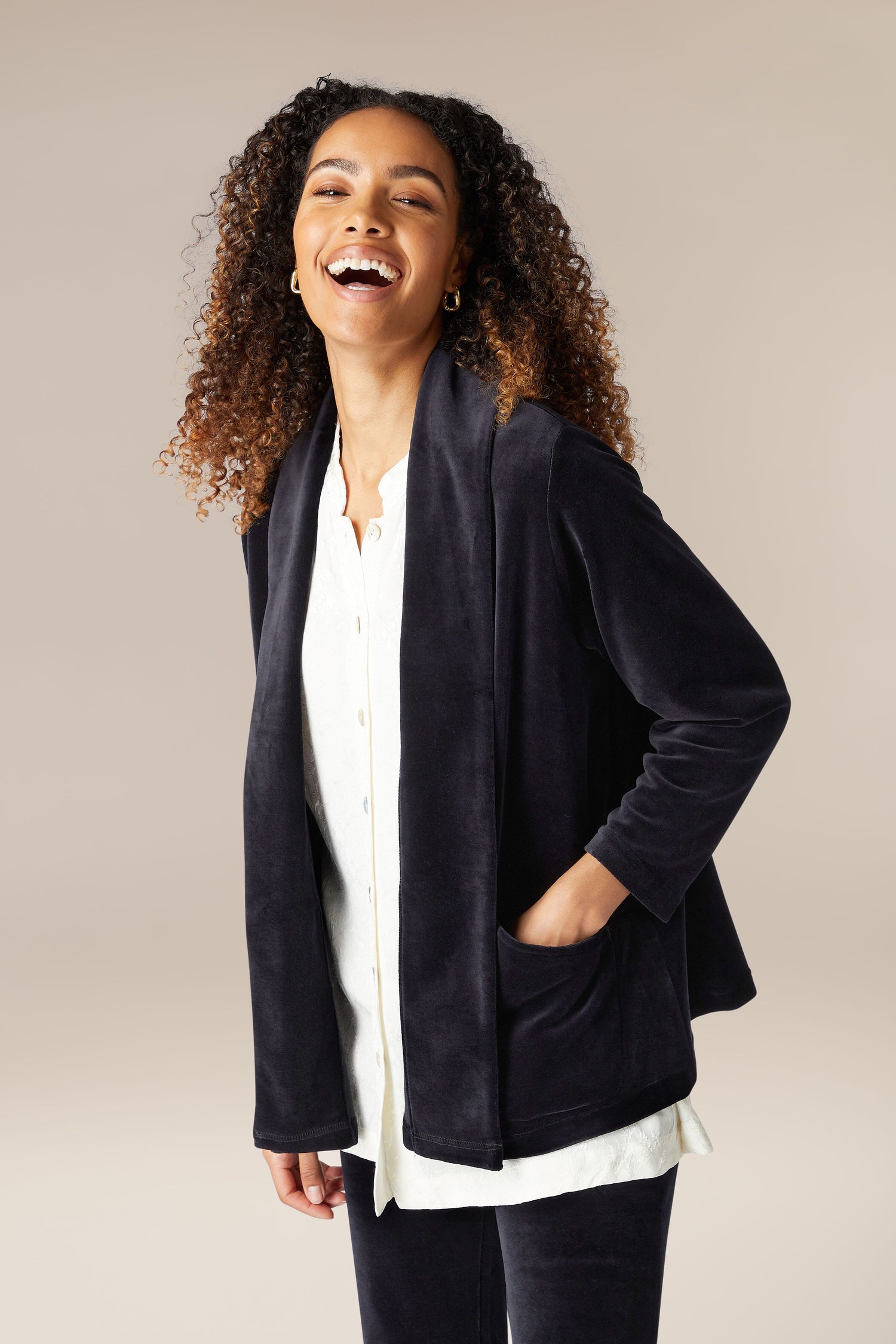 A woman wearing a luxurious Velvet Jersey Relaxed Jacket and white pants.