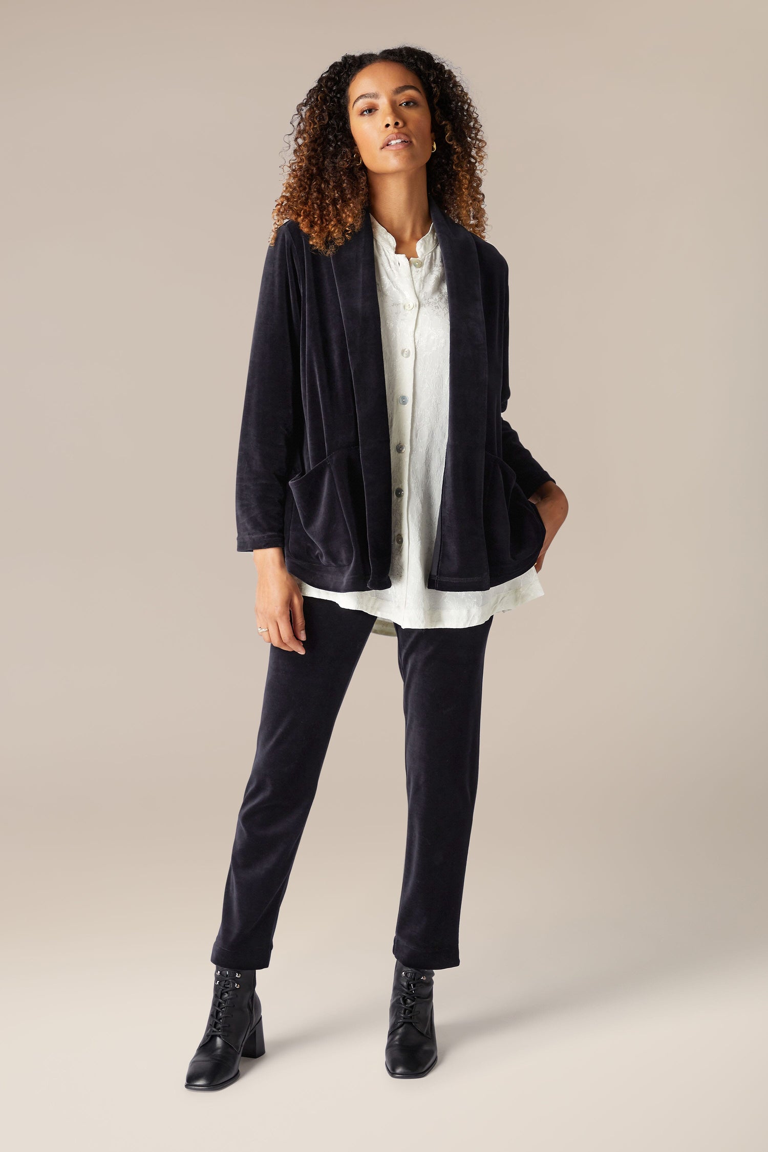 The model is wearing a luxurious Velvet Jersey Relaxed Jacket and white pants.