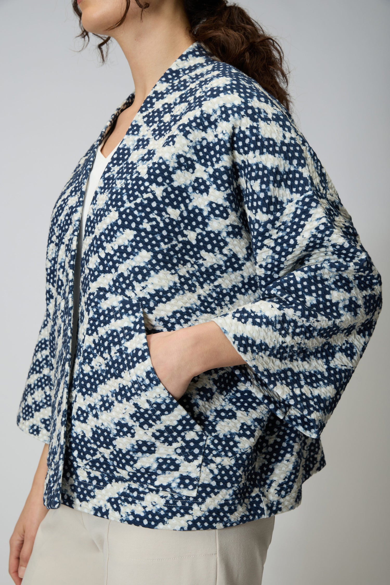 A person wearing the Diamond Tie Dye Jersey Jacket in blue and white with wide sleeves, paired with off-white pants, stands against a plain background.