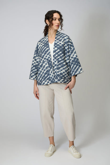 A person wears the Diamond Tie Dye Jersey Jacket in blue and white over a white top, paired with cream cropped pants and white sneakers, standing against a plain light background.