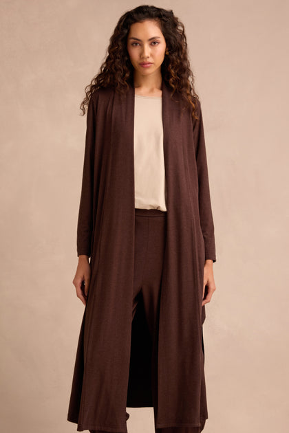 Woman with long curly hair wears a cream top and the Soft Viscose Jersey Long Line Cardi in a kimono-style drape, paired with matching brown pants, standing against a neutral background.