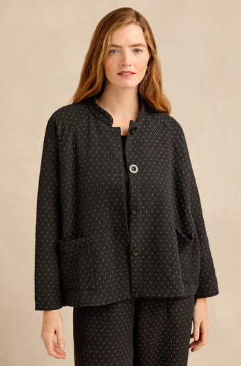 A woman with long, light brown hair wears the Square Jacquard Jacket—workwear-inspired with small dotted patterns and large front pockets—paired with matching pants, standing against a neutral background.