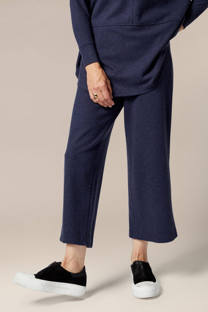A woman wearing a navy Marl Jersey Wide Leg Trouser and cropped pants with a flared silhouette.