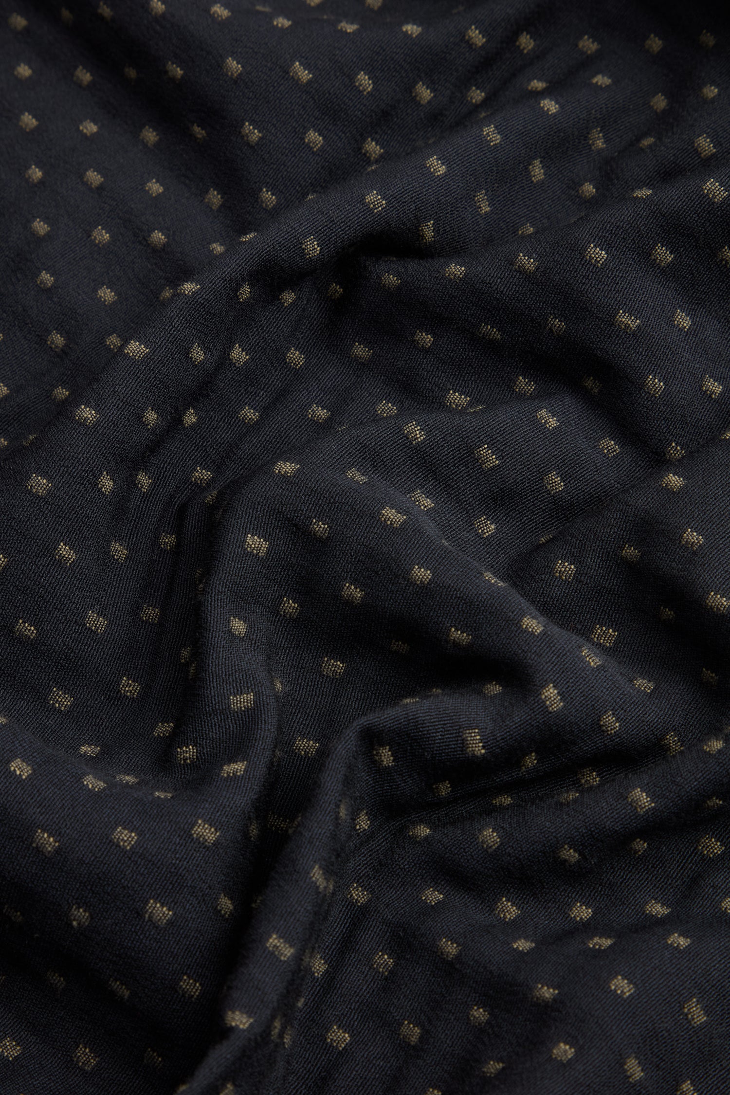 Close-up of the Square Jacquard Bubble Trousers showcasing black fabric adorned with a subtle grid of small, evenly spaced gold dots. The cotton-rich blend appears soft and slightly wrinkled, highlighting the luxurious texture characteristic of this sophisticated design.