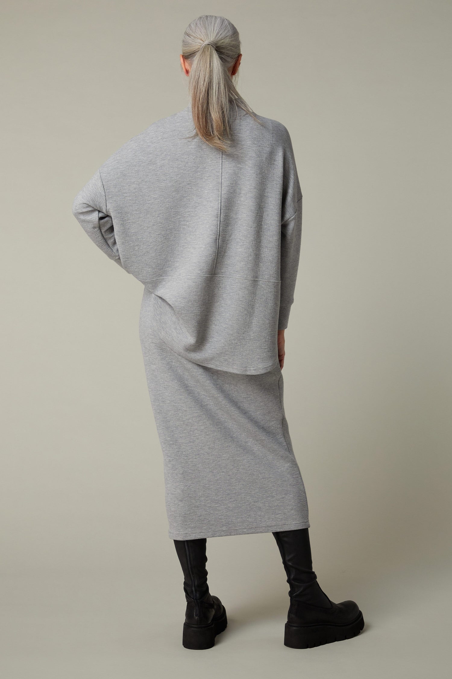 The back view of a woman wearing a Crinkle Jersey Tube Skirt with an elasticated waist.