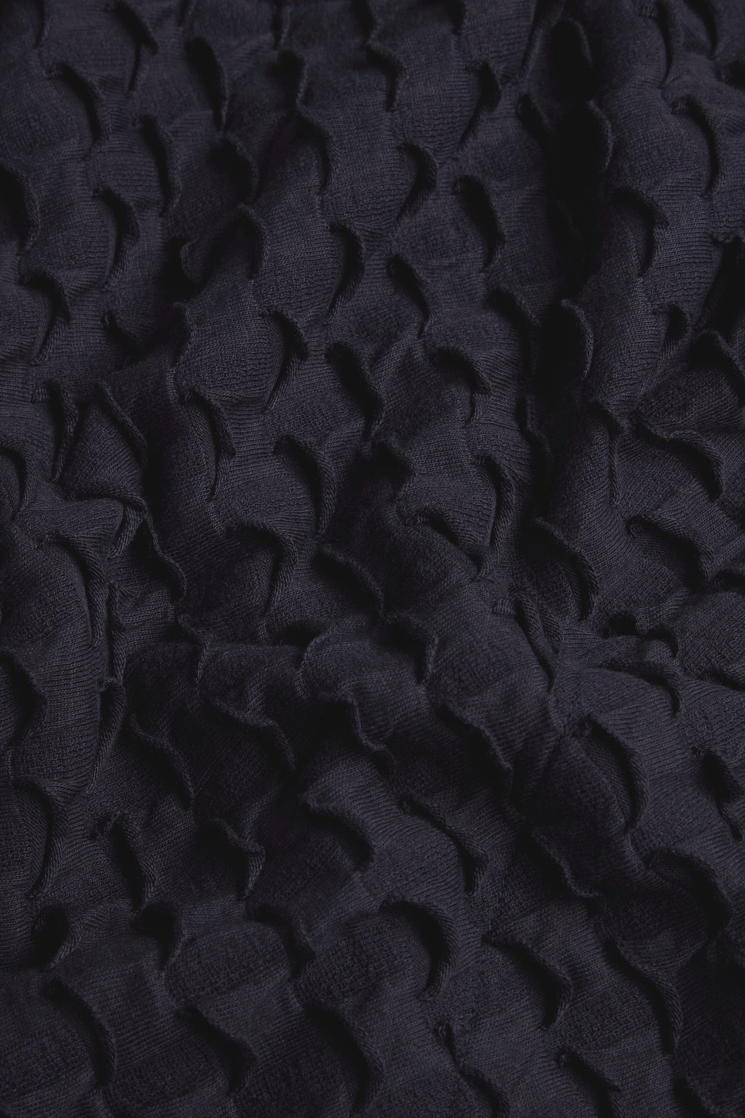 Close-up of dark, textured fabric with an embossed, scallop-like pattern and visible folds—perfect for a sophisticated Pocket Jersey Tube Skirt.