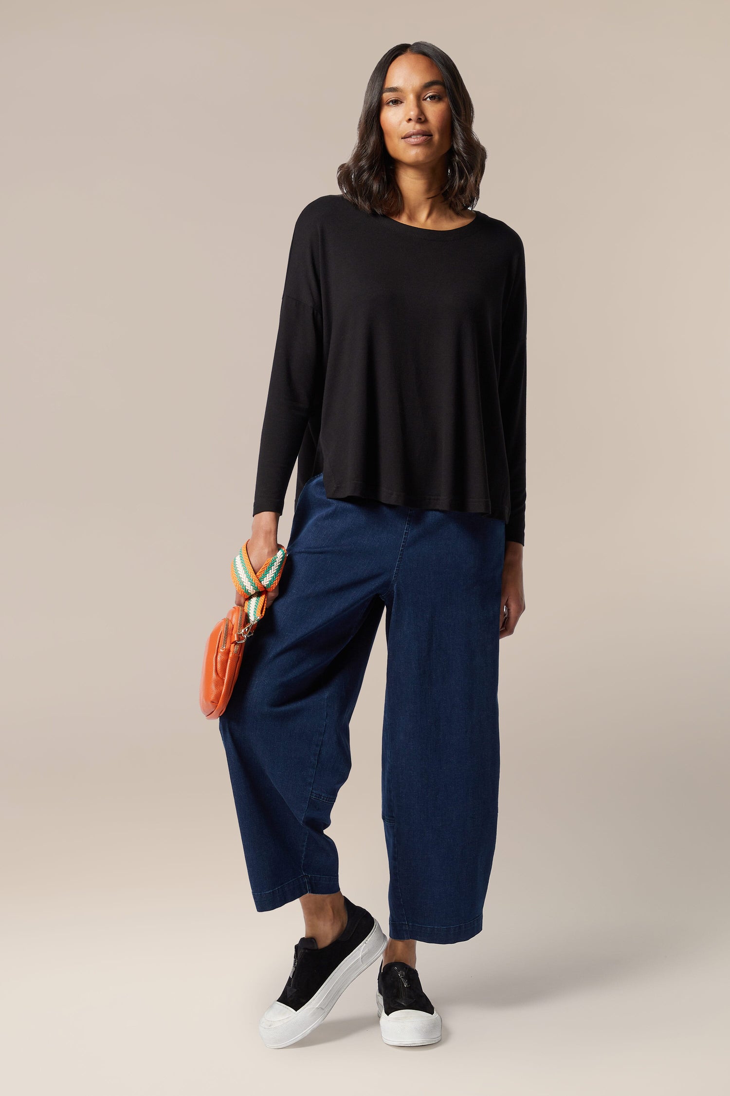 A woman with a Fluid Crepe Relaxed Top in her wardrobe pairs it with blue wide leg pants.