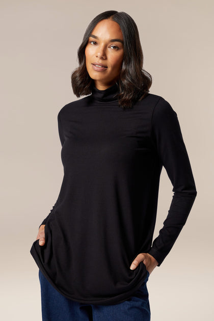 A woman flaunting a Sahara Fluid Crepe Flared Polo Neck top, made with viscose construction.