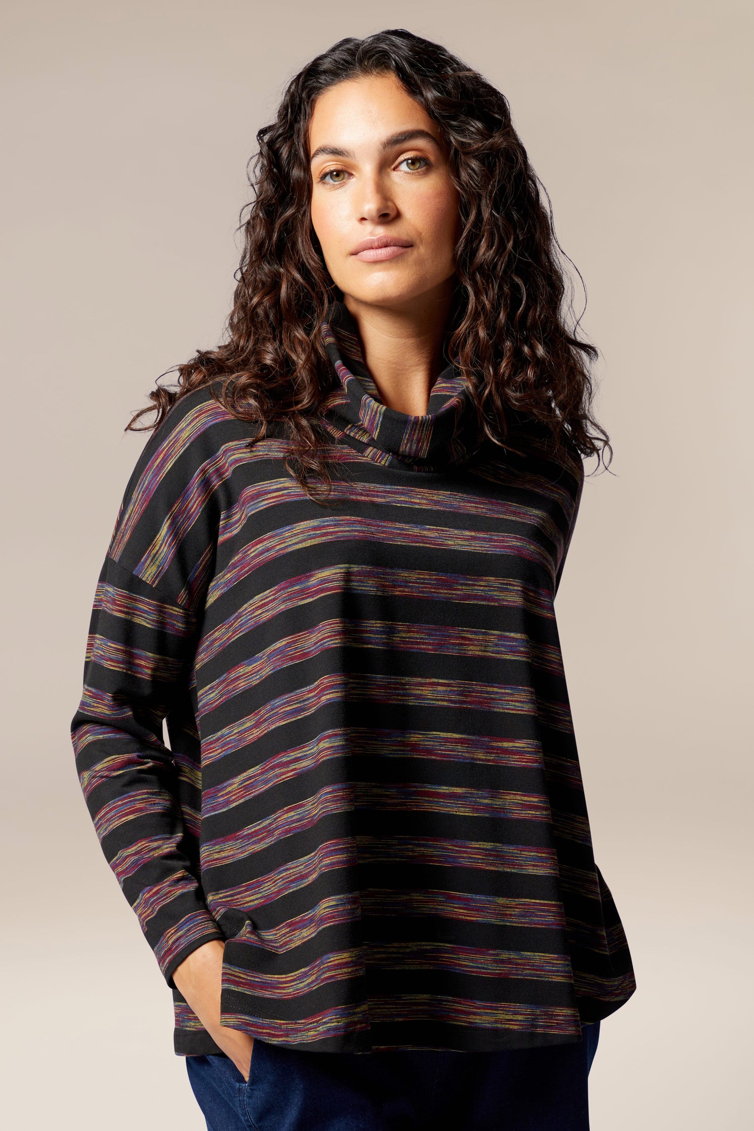 The woman is dressed in a Spacedye Stripe Cowl Neck top, featuring an A-line silhouette and made of plush jersey material.