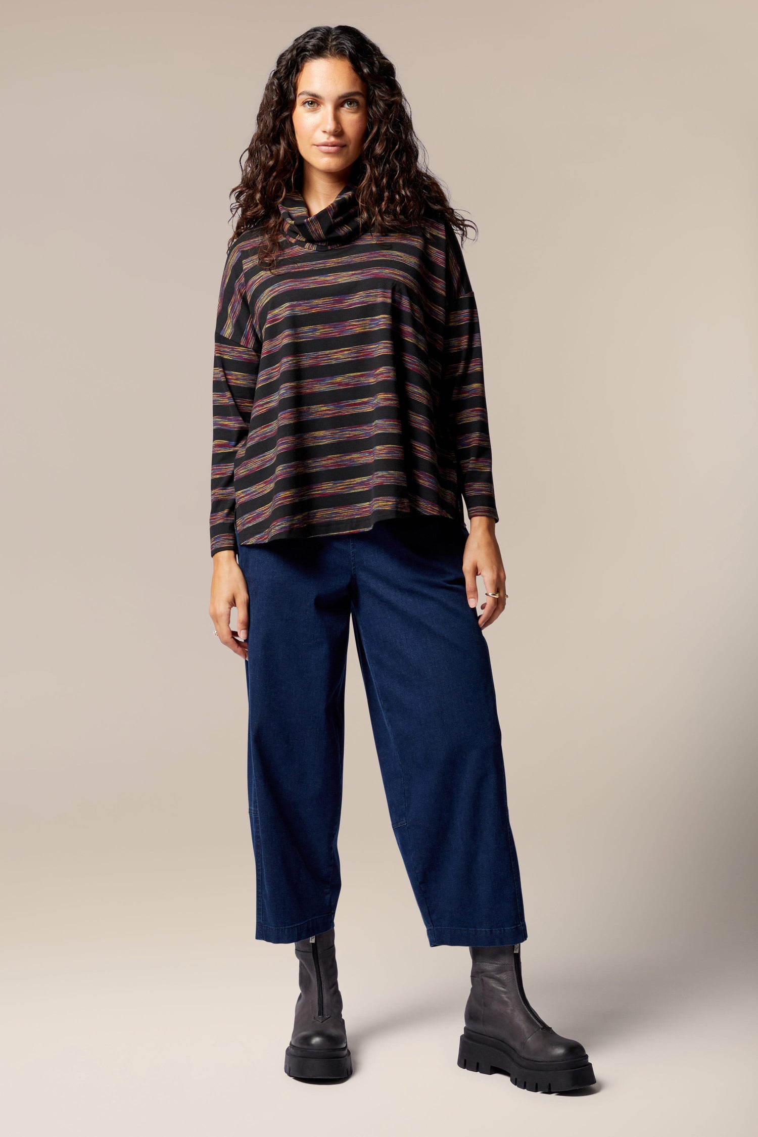 A woman wearing a Spacedye Stripe Cowl Neck top and blue pants.
