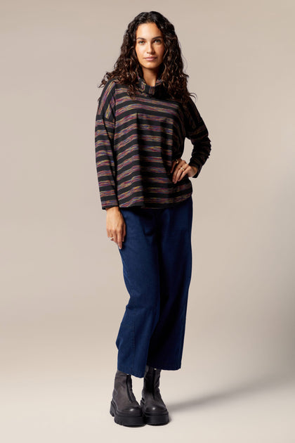 A woman in a Spacedye Stripe Cowl Neck Top, sporting an A-line silhouette and blue pants.