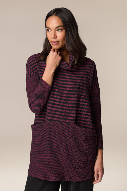 A woman wearing a Crinkle Stripe Cowl Neck Tunic with striped patterns.