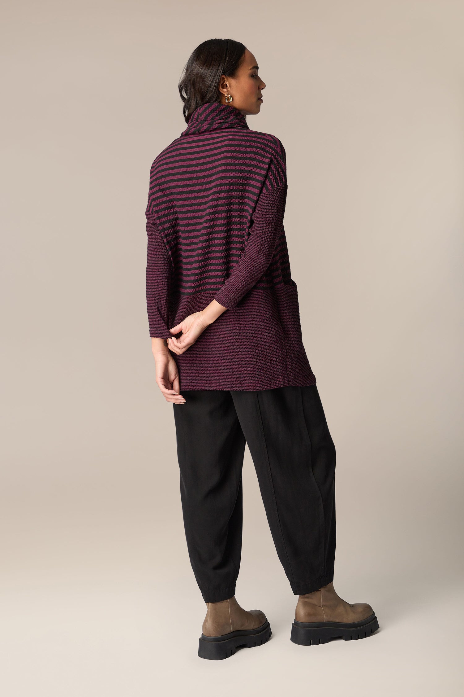 The back view of a woman wearing a Crinkle Stripe Cowl Neck Tunic.