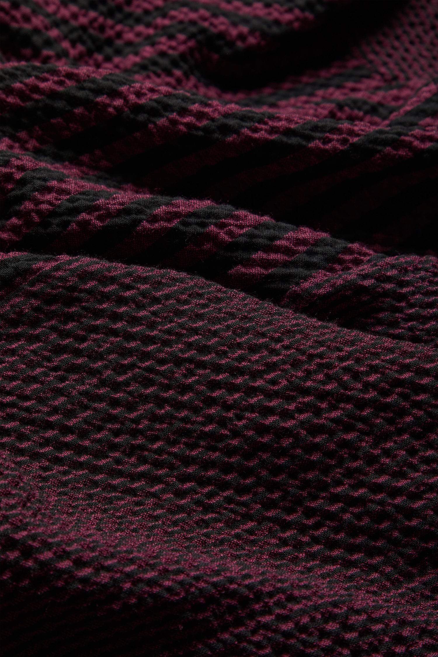 A close up of a Crinkle Stripe Cowl Neck Tunic with burgundy and black knitted fabric with geometric shapes.