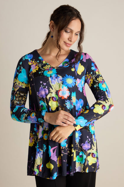 A woman wearing a Blue Bouquet Jersey Top featuring long sleeves and a floral pattern, available in various colors, set against a neutral background.