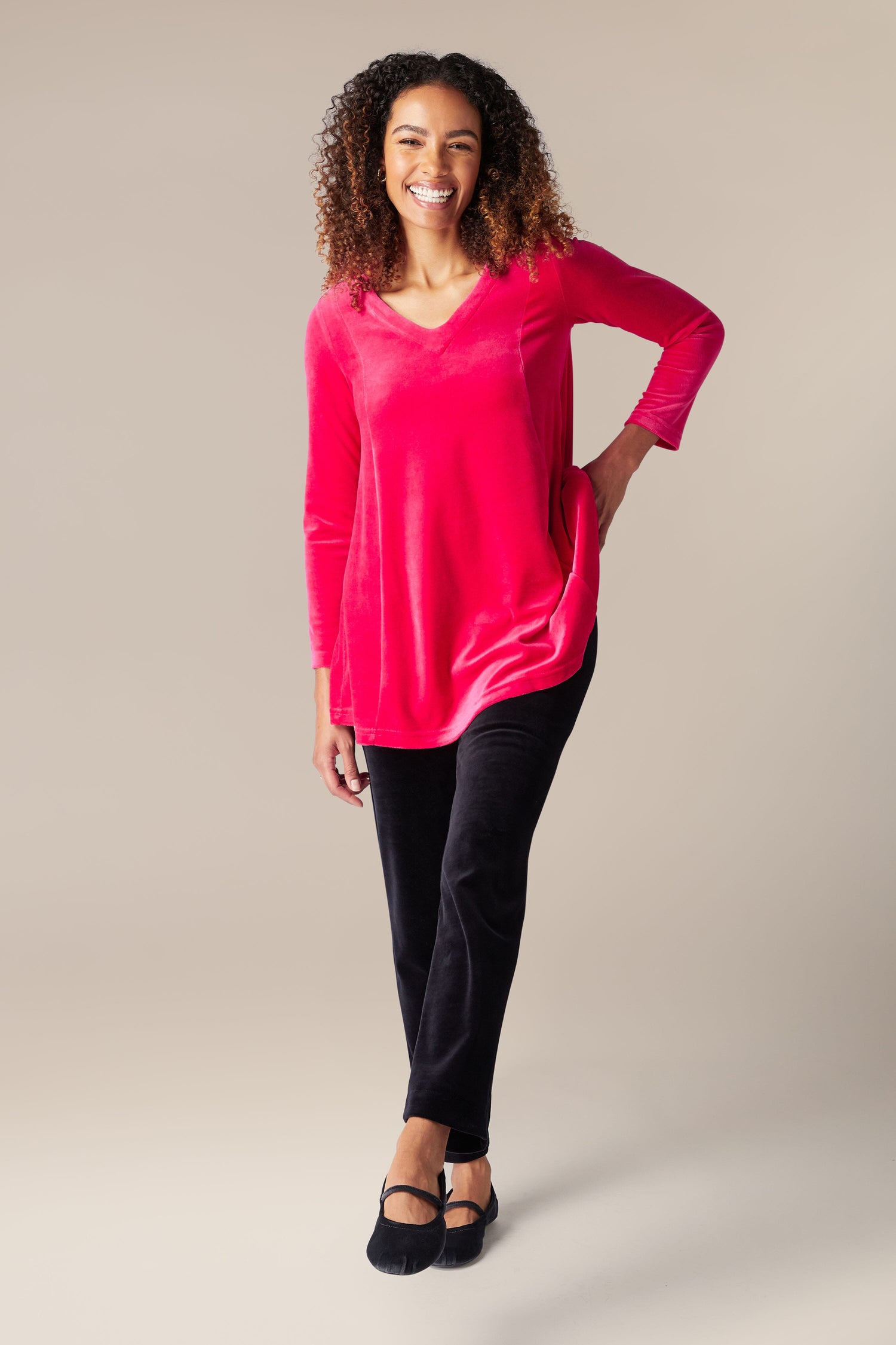 A woman wearing a luxury pink Velvet Jersey Swing Top and black pants.