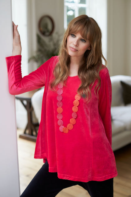 A woman in a luxurious Velvet Jersey Swing Top leaning against a wall.