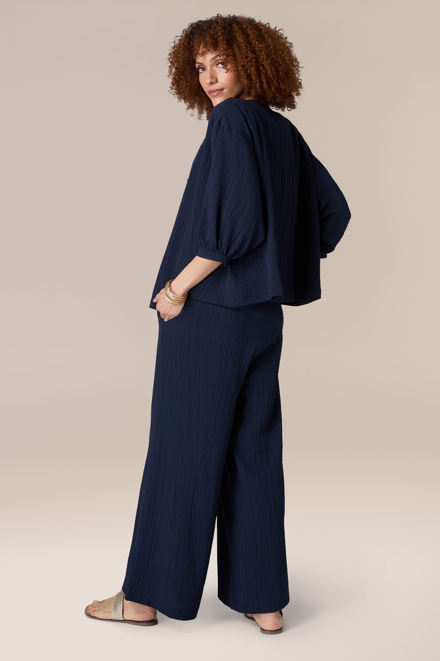 A woman is seen in navy wide leg pants, showcasing an elegant and sophisticated look in the Crinkle Soft Viscose Shirt.