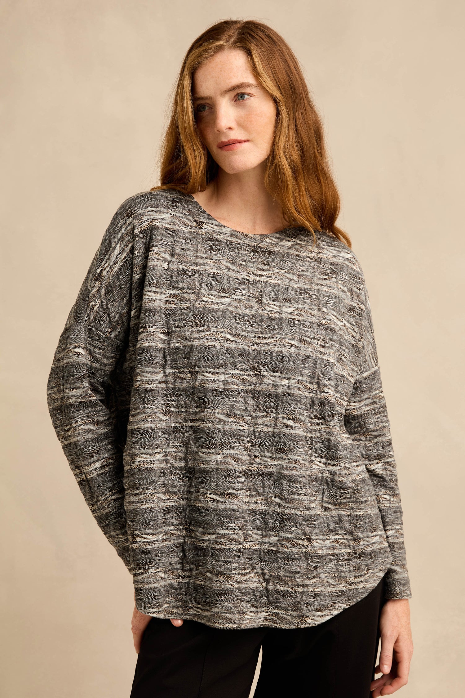 A person with long brown hair is wearing the Abstract Ripple Jersey Boxy Top and black pants, standing against a plain beige background.